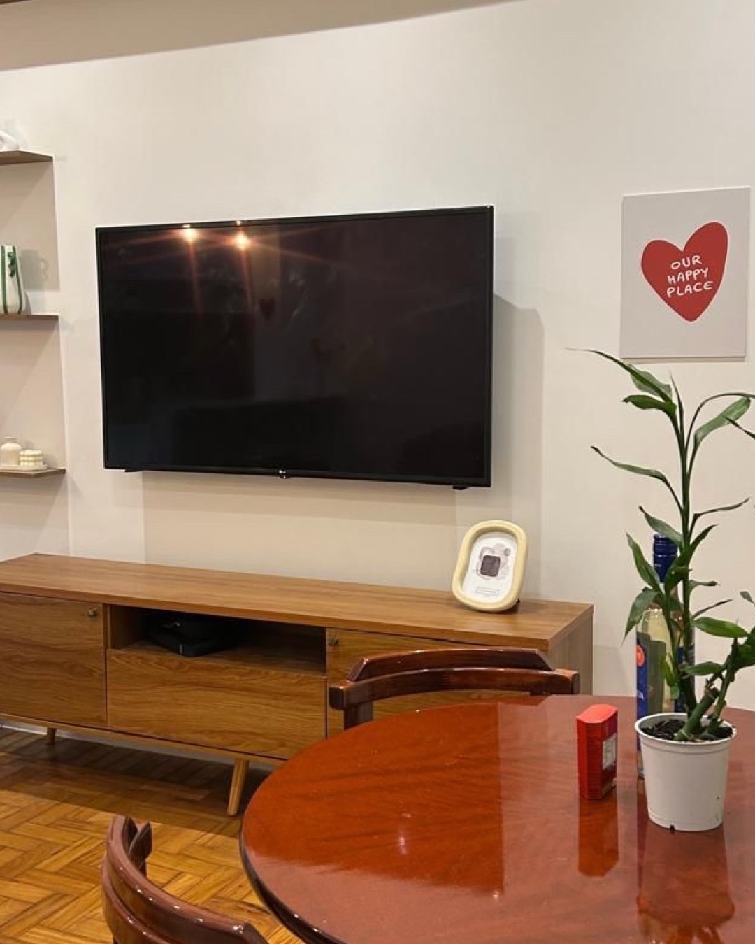 Sala integrada com rack de madeira, TV na parede, nichos e mesa redonda de jantar