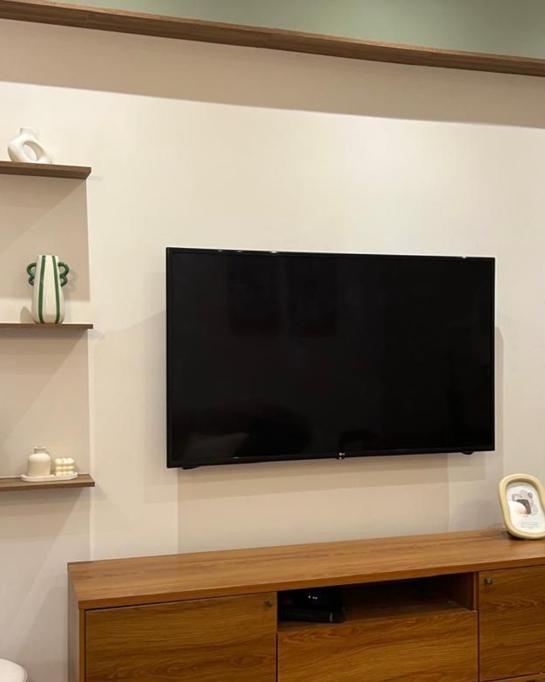 Sala de TV com parede clara, prateleiras de madeira e rack sob medida