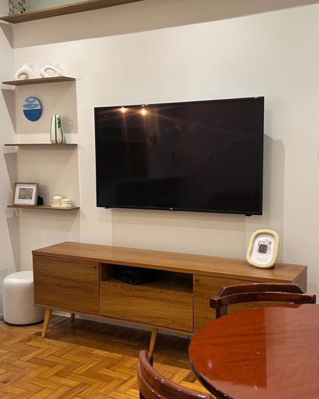 Sala de TV com nichos de madeira, rack baixo e piso em taco espinha de peixe